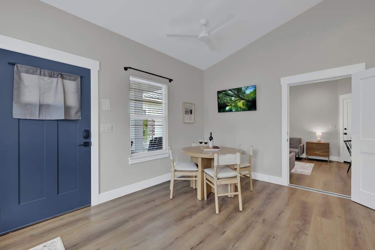 A dining area with a round table and chairs, a ceiling fan, and a door with curtains.