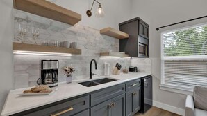 A modern kitchen with a white countertop, grey cabinets, and a built-in oven. - The Grove Combo (Fredericksburg)