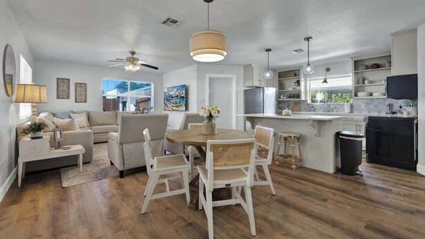 A spacious living area with a dining table, chairs, and a ceiling fan. There is a kitchen area with a refrigerator and a TV. - Weitz Retreat (Fredericksburg)