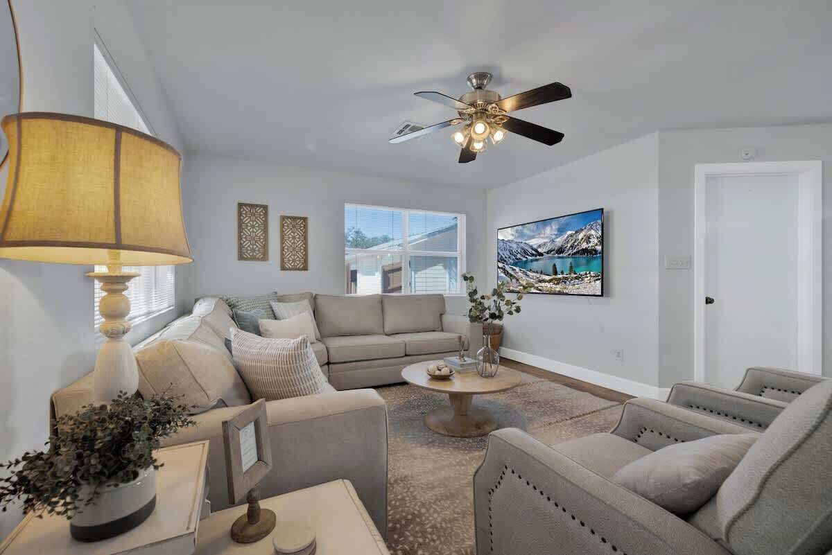 A living room with a ceiling fan, a sofa set, a coffee table, and a painting on the wall.
