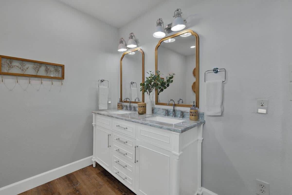 A bathroom with two sinks, a large mirror, and a wooden plant on the counter.