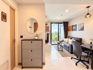 A modern living room with a sofa, coffee table, and a desk with a chair. There is a large mirror on the wall and a door with a handle.