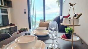 Una mesa de comedor dispuesta con vajilla blanca, una copa de vino y un frutero con cubiertos.