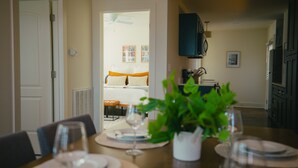 Un comedor con una mesa dispuesta para cuatro, un ventilador de techo y vistas a una sala de estar con un sofá y una mesa de centro.