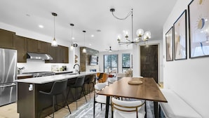 A modern kitchen with a central island, dark wooden cabinets, stainless steel appliances, and pendant lighting. - Modern Townhome, Amazing views from the Rooftop Hot tub 541 (Silverthorne)