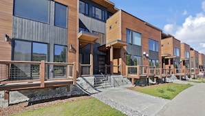 A modern multi-story residential building with large windows, wooden balconies, and a stone foundation. - Modern Townhome, Amazing views from the Rooftop Hot tub 541 (Silverthorne)