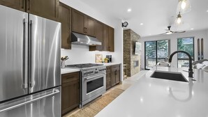 A modern kitchen with stainless steel appliances, wooden cabinets, and a large island. - Modern Townhome, Amazing views from the Rooftop Hot tub 541 (Silverthorne)