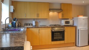 Une cuisine moderne avec des meubles en bois, une cuisinière à gaz, un four à micro-ondes et un réfrigérateur.