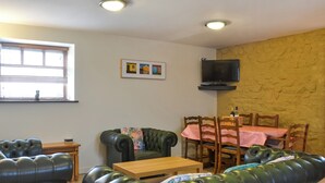 Un salon avec un canapé, une table en bois et un téléviseur fixé au mur.