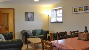 Un salon chaleureux avec un canapé, une table en bois et une fenêtre équipée de stores.
