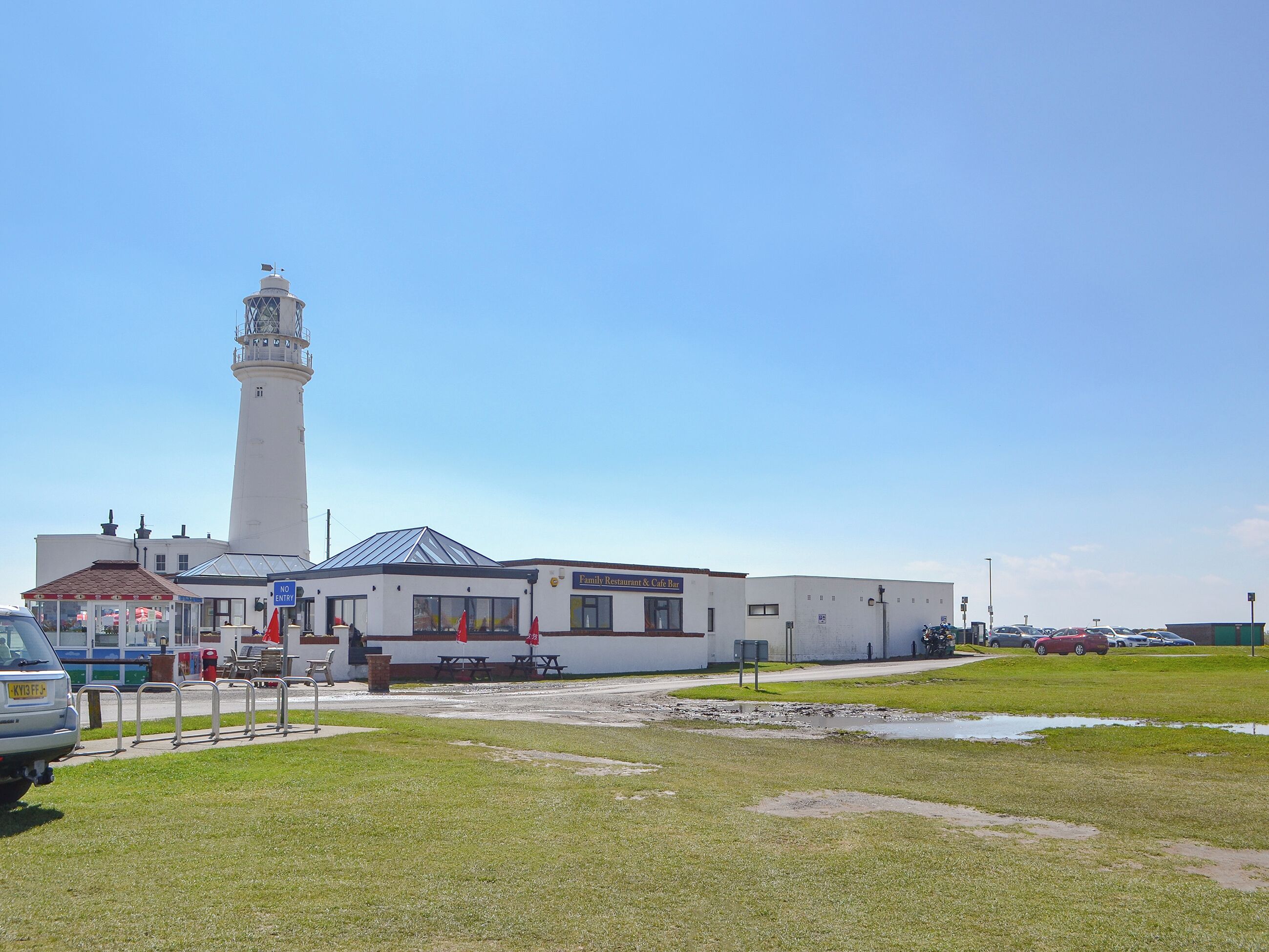 A lighthouse with a white tower and a building with a glass roof in front.