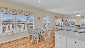 A spacious kitchen with large windows, white cabinetry, and wicker chairs. - Ocean Views and Pool, King Bed, Beach Access at end of Driveway! (Emerald Isle)