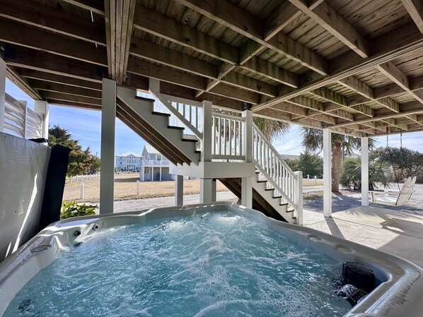 Un jacuzzi bajo una pérgola de madera con una escalera que lleva a un nivel superior.