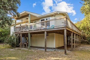 Stunning two-story residence with a spacious balcony and gabled roof, set amidst lush vegetation.