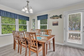 Enjoy meals in this dining room with a wooden table and chairs, a chandelier, and a fish-shaped decoration.