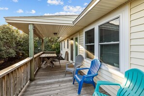 Enjoy outdoor dining or relaxation on the covered deck with a wooden table and Adirondack chairs.