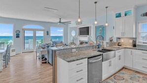 A modern kitchen with white cabinets, granite countertops, and a view of the ocean. - 5BR, Ocean Front, 1/2 Duplex! (Emerald Isle)