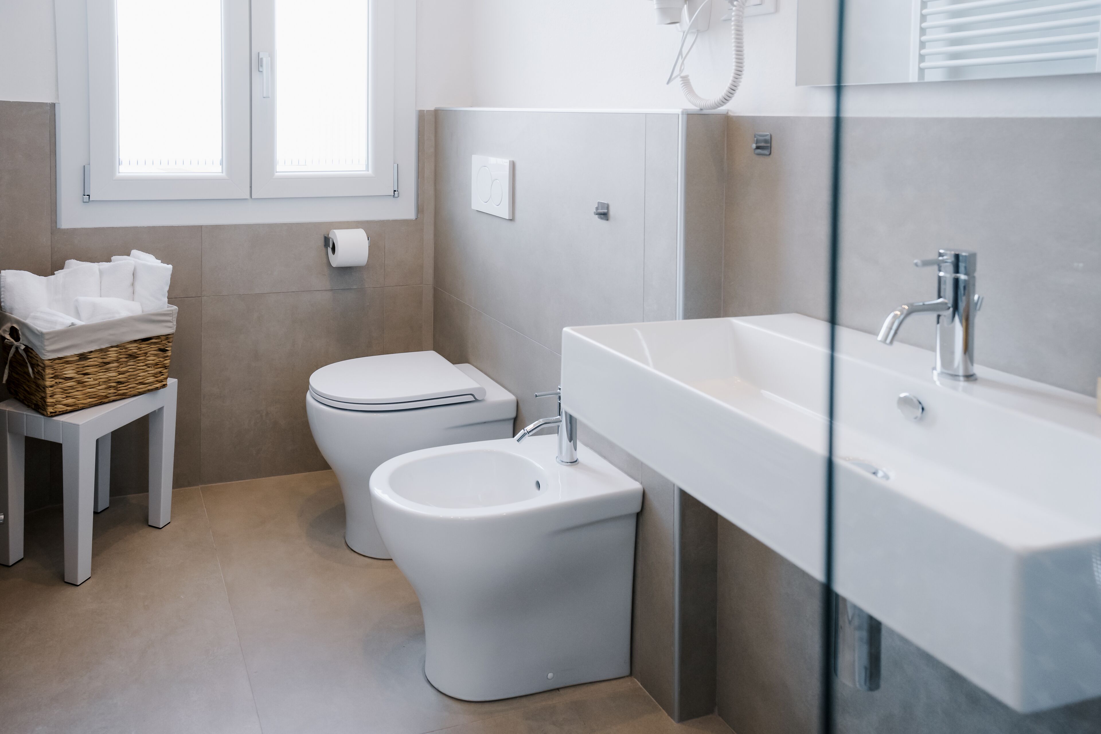 A modern bathroom with a toilet, bidet, and a large sink.