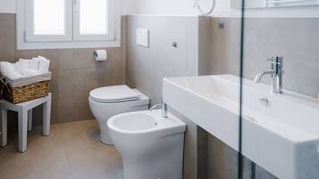 A modern bathroom with a toilet, bidet, and a large sink.