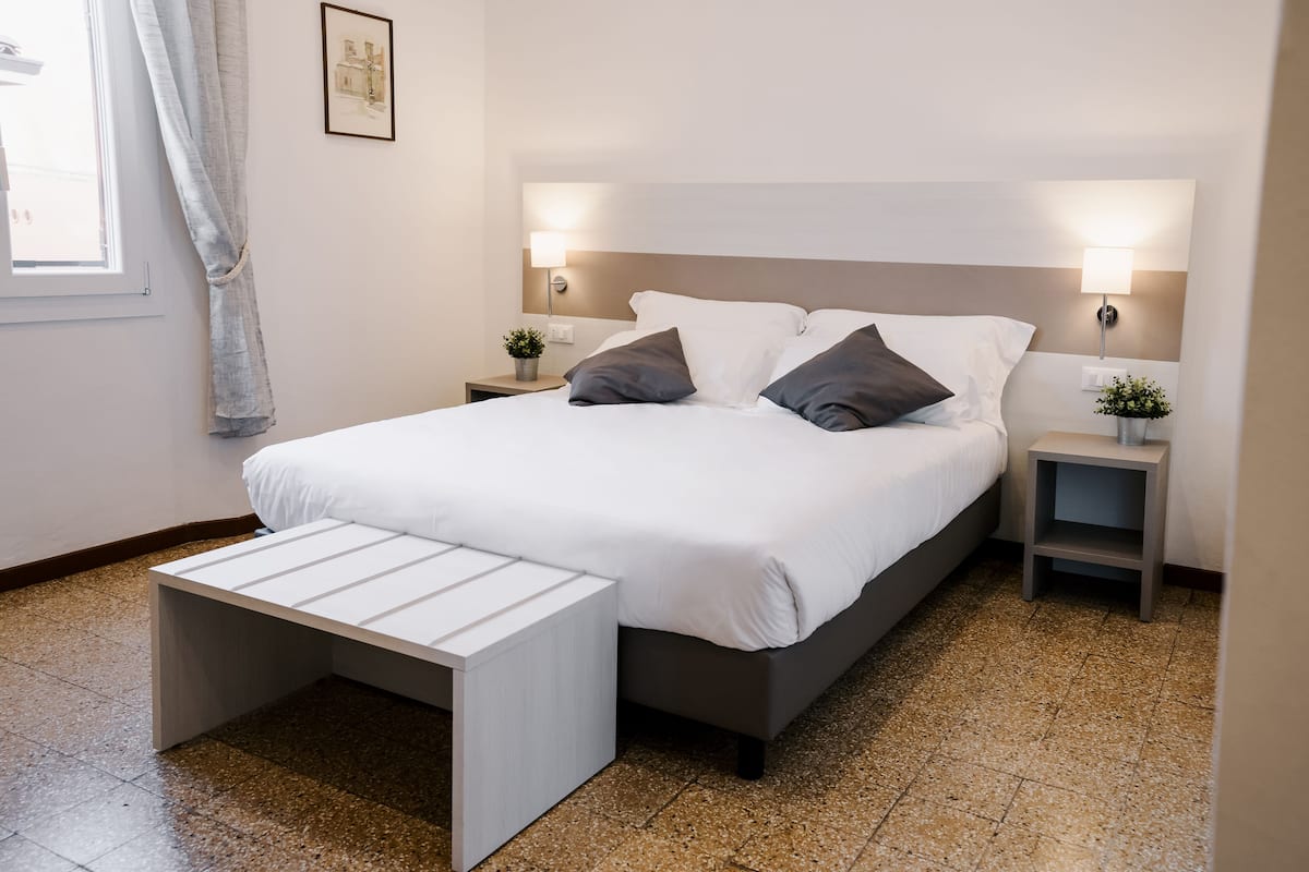 Une chambre à coucher moderne avec un lit, des tables de chevet, une petite table et une petite plante.