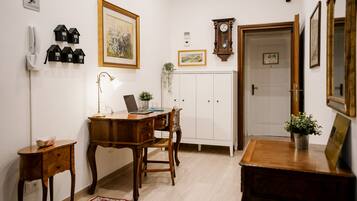 Ein Zimmer mit Schreibtisch aus Holz, einem Laptop, einem Telefon, einem Schrank und einer Tür.
