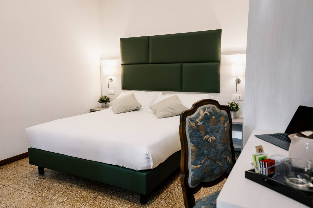 Une chambre d’hôtel avec un lit, un bureau avec un ordinateur portable et une chaise.
