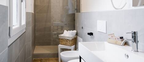A modern bathroom with a shower, toilet, and sink.