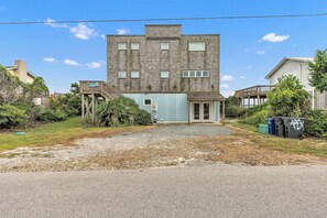 A two-story building with a flat roof, a small porch, and a gravel driveway. - Hot TUB & Pet Friendly, Ocean Front, Covered Decks! (Emerald Isle)