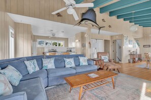 A living room with a blue sofa, wooden coffee table, and a ceiling fan. - Hot TUB & Pet Friendly, Ocean Front, Covered Decks! (Emerald Isle)