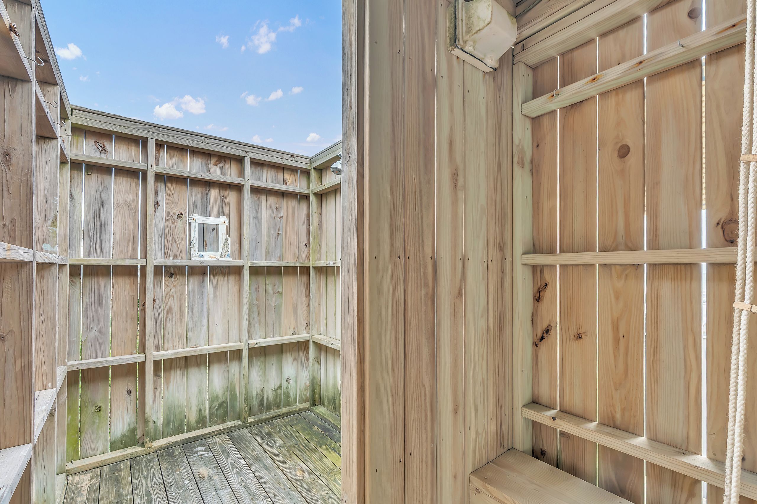 A private outdoor shower offers the perfect place to rinse off after a day at the beach or pool, enclosed by natural wood walls and open to the sky above.