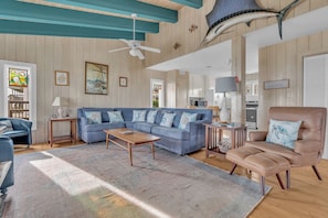 A spacious living room with a blue sofa, a brown armchair, and a wooden coffee table.