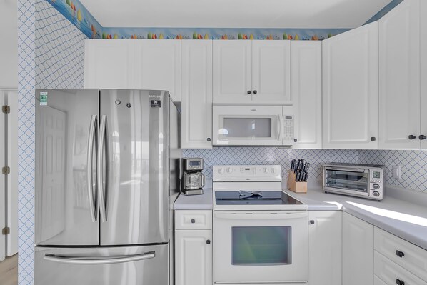 A modern kitchen with white cabinets, stainless steel appliances, a microwave, oven, and a toaster. - Dogs OK! 3BR/Bonus Room - Ocean Front! (Emerald Isle)