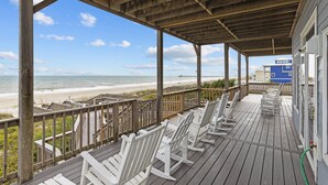 A wooden deck with white chairs overlooking a beach. - 4BR Ocean Front - King MBR with Views! (Emerald Isle)