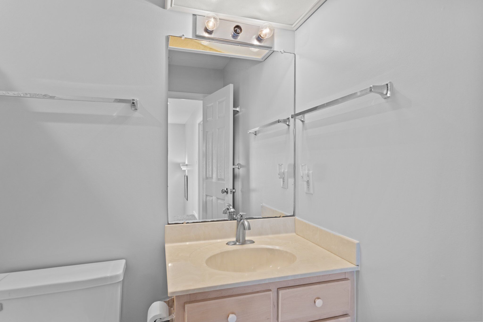 A bathroom with a sink, mirror, towel rack, and a toilet.