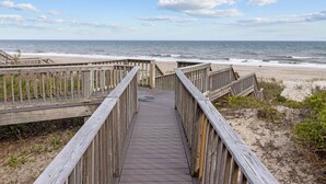 Une promenade en bois qui mène à une plage d’où l’on a une vue dégagée sur l’océan.