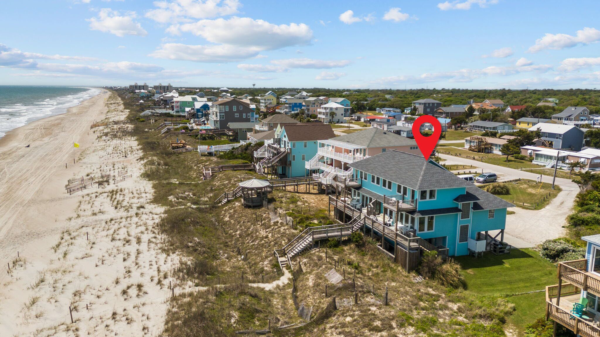 A coastal residential area with houses, a beach, and a pier.