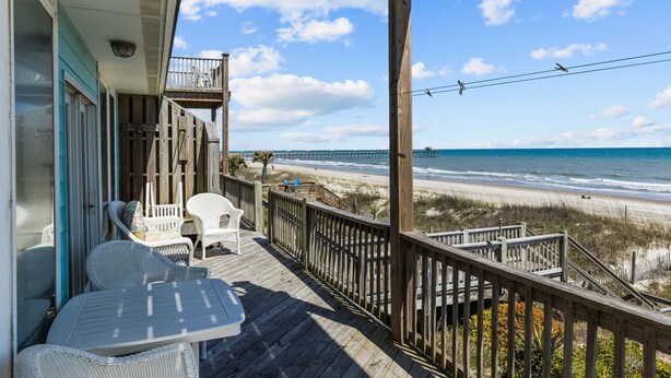 A wooden deck with outdoor furniture overlooking a beach. - 4BR Ocean Front Dog Friendly Duplex - Rent both sides! (Emerald Isle)