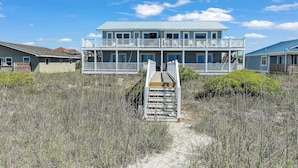 A beachfront house with a wooden deck, a staircase leading to a balcony, and a clear view of the ocean. - 4BR Ocean Front - Dogs OK! (Emerald Isle)