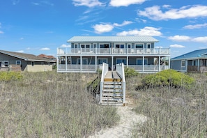 A beachfront house with a wooden deck, a staircase leading to a balcony, and a clear view of the ocean. - 4BR Ocean Front - Dogs OK! (Emerald Isle)