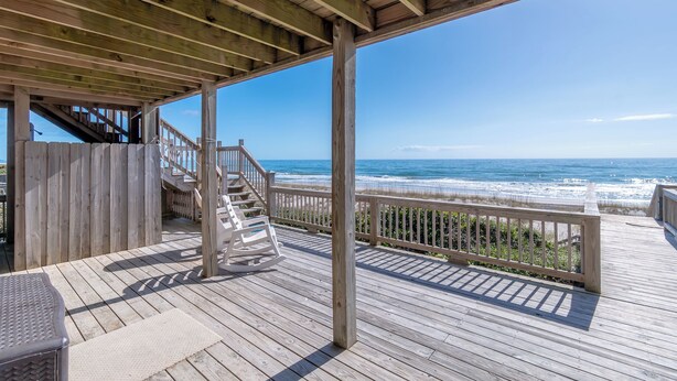 A wooden deck with a wooden staircase leading to a covered area overlooking the ocean. - 4BR Ocean Front - DOG OK - Close to town! (Emerald Isle)