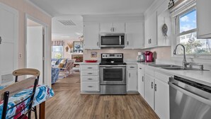 Une cuisine moderne avec des armoires blanches, des appareils en acier inoxydable et un plancher en bois.