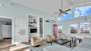 A spacious living room with a large window, a ceiling fan, and a view of the outside. - 3BR - One Level - SUPER CUTE - Ocean front & DOGS OK!! (Emerald Isle)