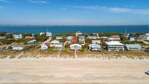 A coastal residential area with houses along the beach, a clear sky, and the ocean in the background. - 3BR - One Level - SUPER CUTE - Ocean front & DOGS OK!! (Emerald Isle)