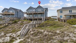 A beachfront property with multiple houses, each featuring wooden decks and stairs leading to the beach.