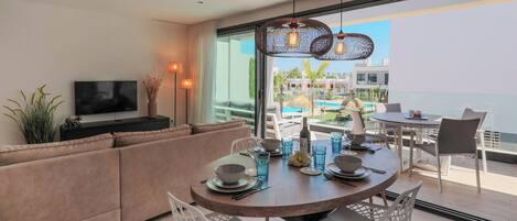 A modern dining area with a round table set for four, a sofa, and a TV on a stand.