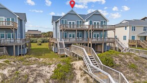 A beachfront property with multiple-story buildings, wooden decks, and outdoor seating areas. - 4BR duplex close to town and ocean front! (Emerald Isle)