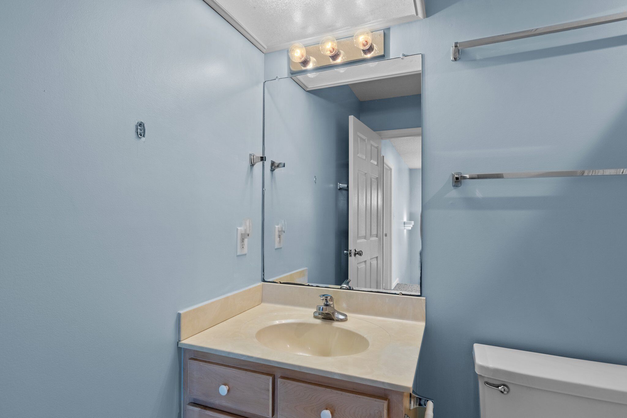 Une salle de bain avec un lavabo beige, un miroir et des toilettes blanches.