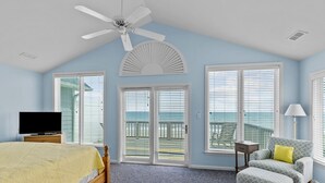 A bedroom with a bed, a chair, a TV, and a ceiling fan. - 4BR duplex close to town and ocean front! (Emerald Isle)