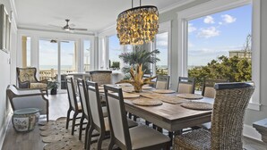 Un vaste espace dédié à la salle à manger, avec une grande table, de nombreuses chaises et un lustre original.