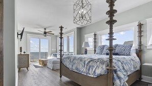 Une chambre spacieuse avec un grand lit, un ventilateur de plafond et une vue sur l’extérieur.